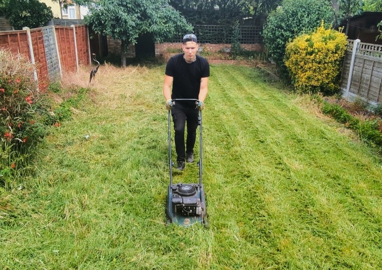 Person mowing a garden lawn with a push mower